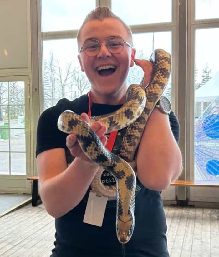 Nolan Asplund rit aux éclats en tenant un grand faux cobra aquatique.