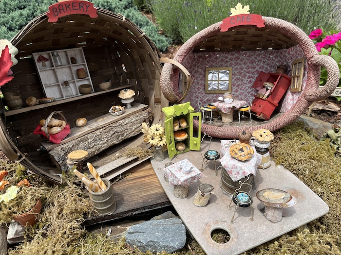 Posés de côté sur des bûches, deux paniers dont l'intérieur est décoré pour représenter les pièces d'une maison.
