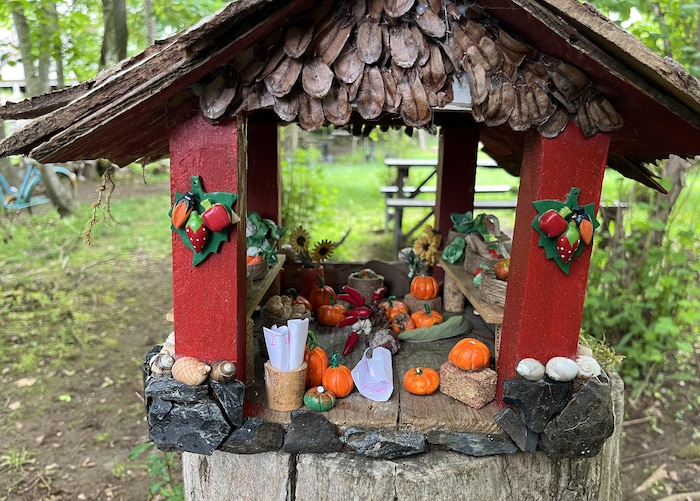 Des citrouilles et des piments miniatures décoratifs dans une petite cabane en bois, et des petits bouts de papier.