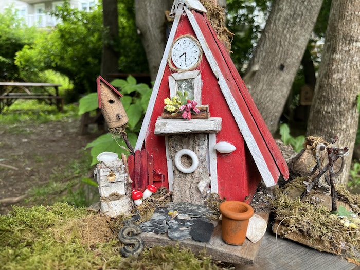 Une cabane miniature rouge au toit pointu.