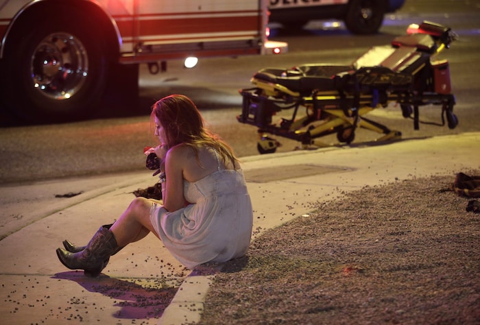 Une femme se remet lentement de ses émotions près d'un véhicule d'urgence. 
