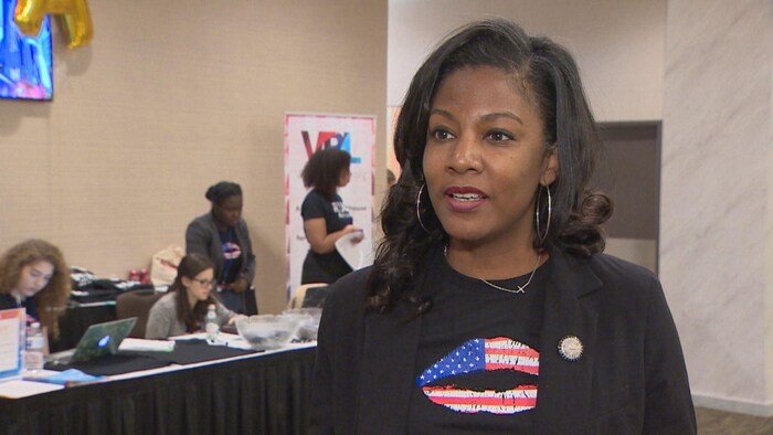 Tishaura Jones porte un veston noir par-dessus un t-shirt de la même couleur sur lequel est imprimé la marque d'un baiser aux couleurs du drapeau des États-Unis.