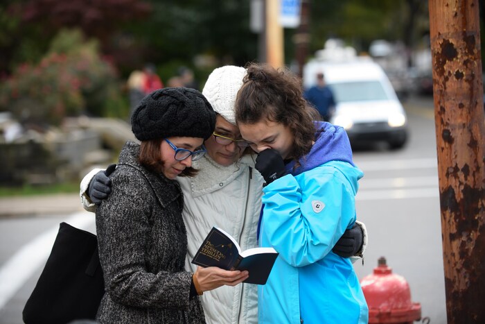 Trois femmes se recueillent en lisant un livre de prières juives près de la synagogue où a eu lieu la fusillade meurtrière, à Pittsburgh.