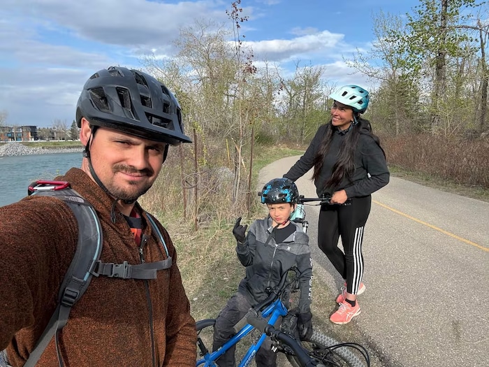 Une famille portant des équipements de protection pour faire du vélo se tient sur une piste cyclable.