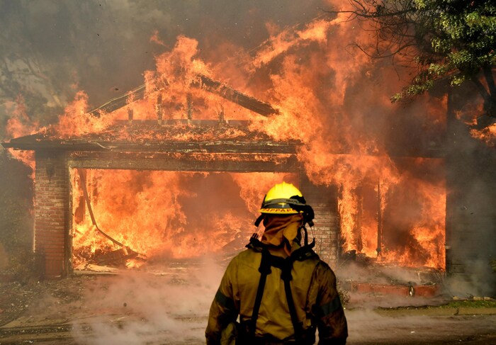 Un pompier devant une maison en flammes.