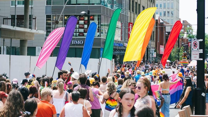 Des bannières de différentes couleurs se dressent au-dessus d'une rue fermée à la circulation remplie de centaines de personnes.