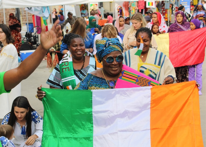 Des personnes en vêtements traditionnels de la Côte d'Ivoire marchent en présentant le drapeau du pays.