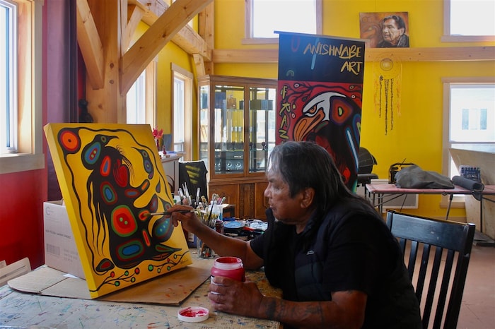 Un artiste peint une toile colorée dans son atelier.