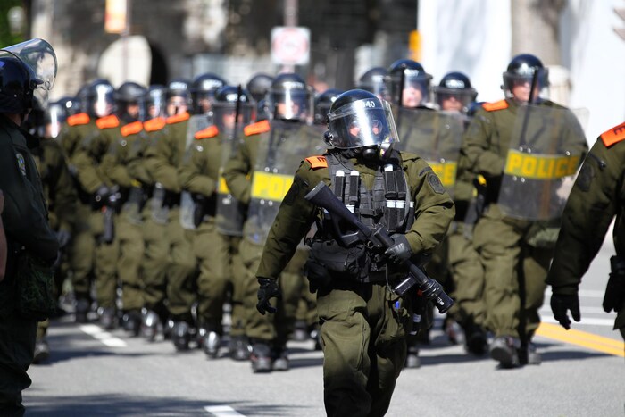 Des policiers en uniforme vêtus de masques à gaz