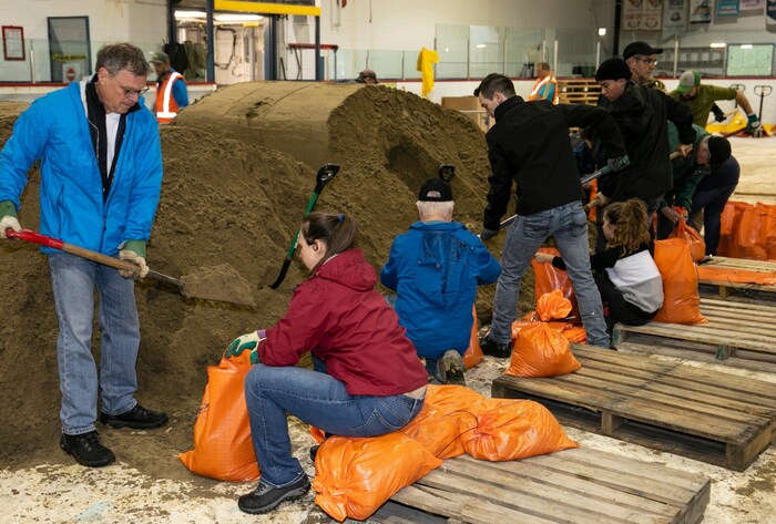 Des gens remplissent des sacs de sable.