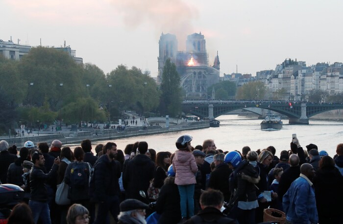 Des gens regardent la fumée s'échapper de la cathédrale Notre-Dame pendant l'incendie qui s'est déclaré le 15 avril 2019. 
