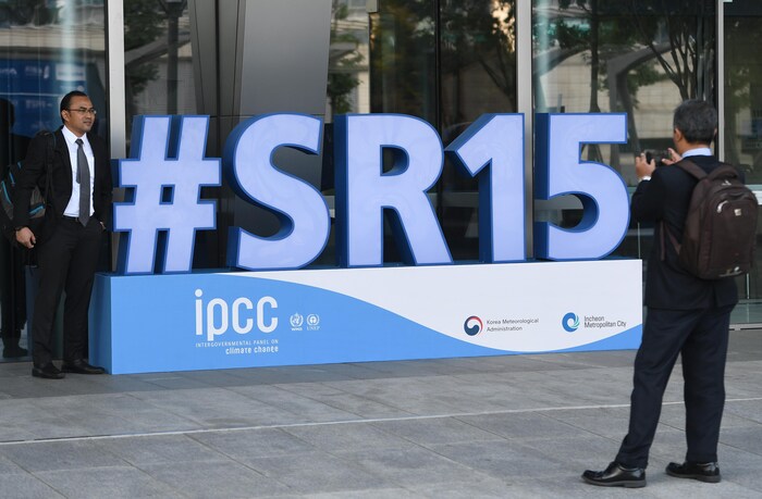 Un participant à la rencontre du Groupe d’experts intergouvernemental sur l’évolution du climat (GIEC) de Corée du Sud prend la pose devant un publicité de l'événement
