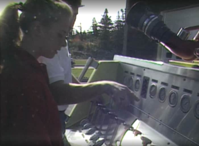 Une jeune femme se fait expliquer par un homme le fonctionnement d'une machine.