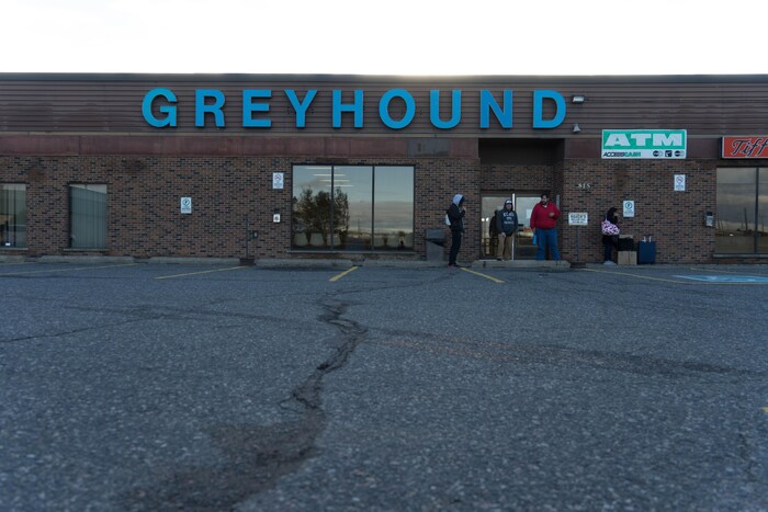 Des passagers attendent devant le bâtiment Greyhound.