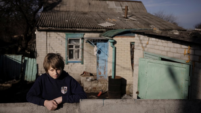 Un adolescent devant une vieille maison. 