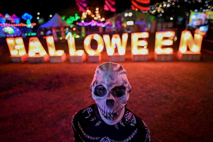 Une personne déguisée en squelette devant un écriteau d'Halloween. Photo prise à Cali en Colombie le 29 octobre 2021.