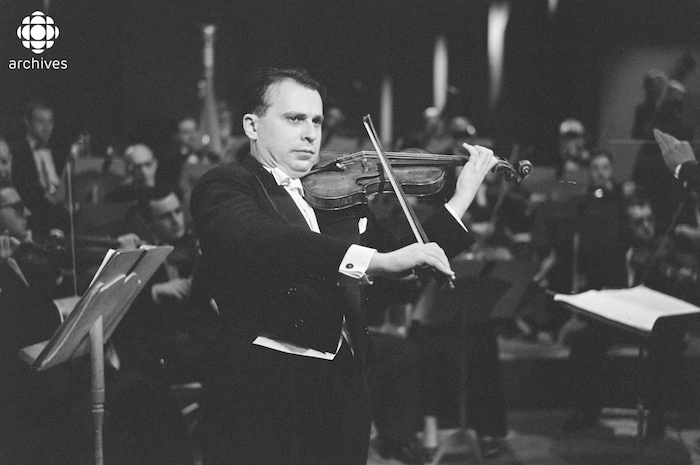 Henryk Szeryng jouant du violon devant un orchestre.