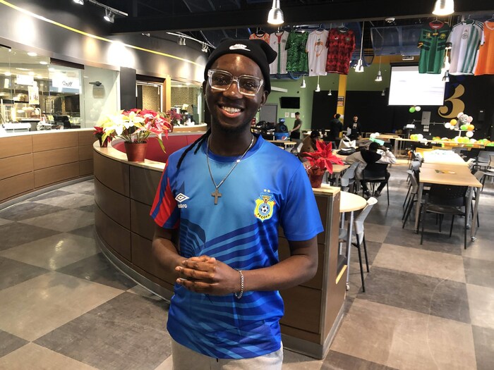 Héritier Masimengo vêtu d'un maillot de la Fédération Congolaise de Football-Association. Il regarde vers la caméra et sourit.
