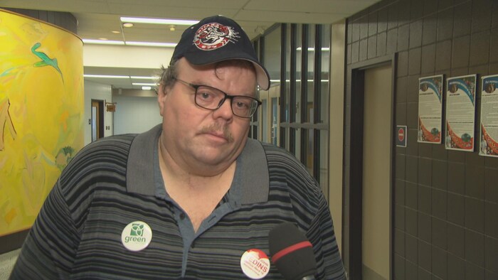 Un homme avec un casquette en entrevue avec Radio-Canada dans un couloir. 