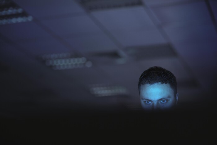Un homme dans le noir devant un ordinateur.