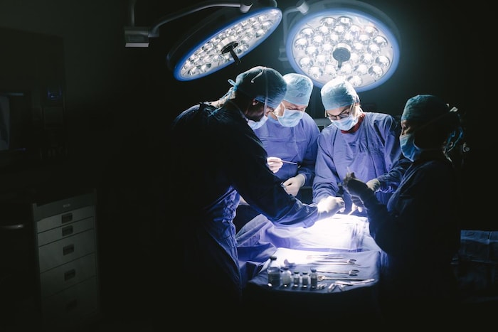 Vue générale d'une salle d'opération avec quatre membres d'une équipe médicale à l'oeuvre.