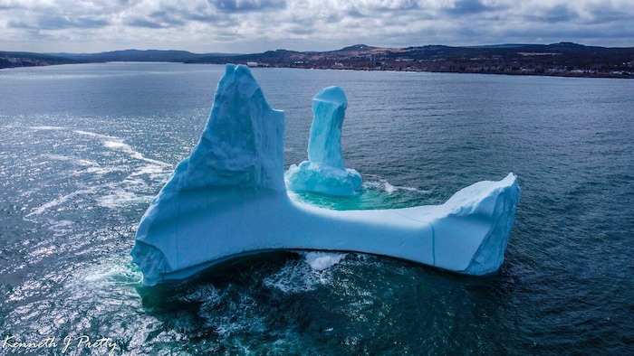 Photo prise par drone d'un iceberg de forme phallique dérivant sur l'océan.