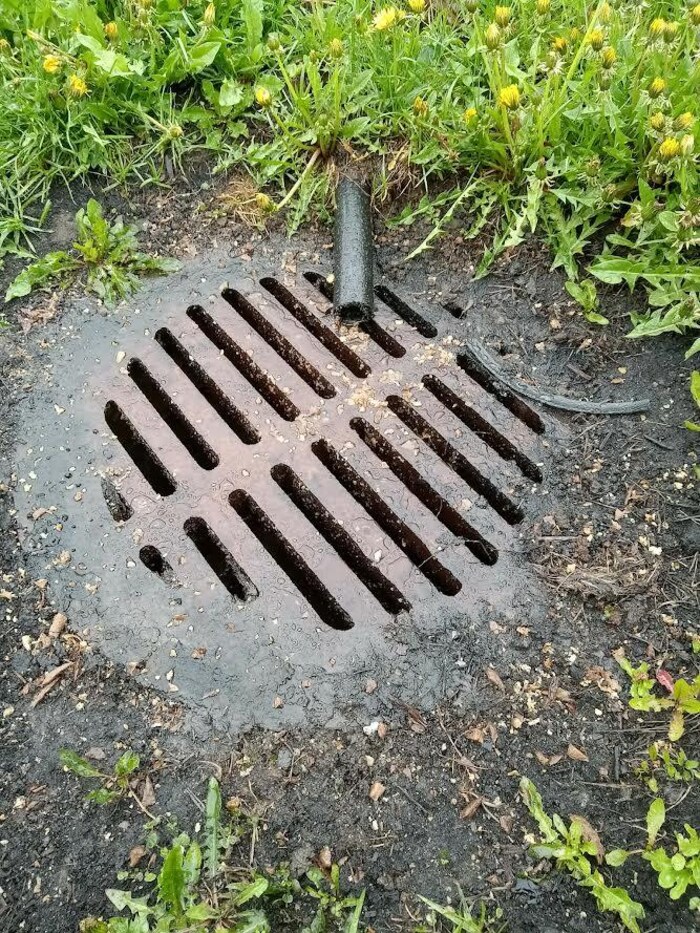 Une bouche d'égout avec un tuyau.