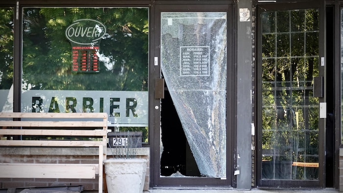 Une vitrine d'un salon de coiffure vandalisée.