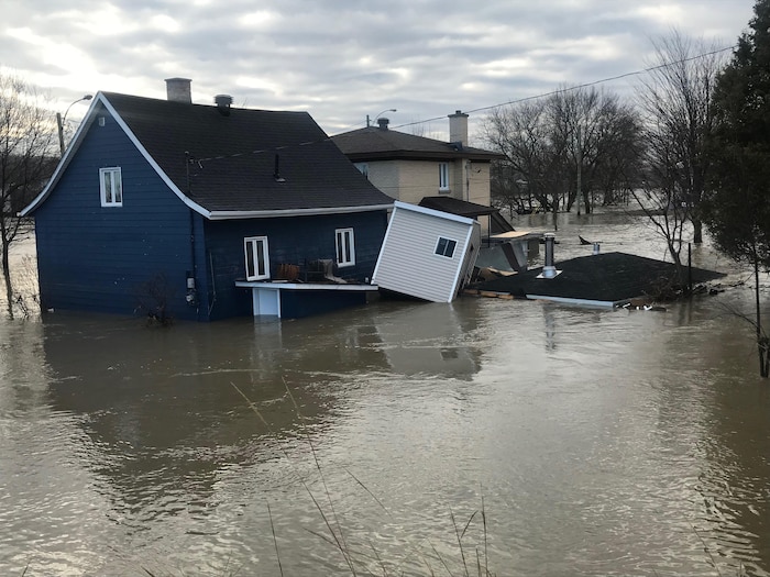 Deux maisons sont entourées par les eaux de la rivière Chaudière. On aperçoit le toit d’un cabanon qui est presque entièrement submergé.