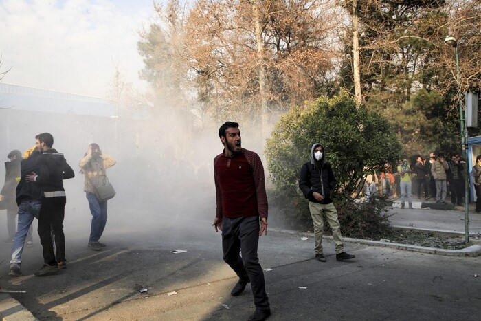 Sur cette photo obtenue par Associated Press, des étudiants manifestent dans l'enceinte de l'Université de Téhéran alors qu'une grenade fumigène est lancée par la police antiémeute iranienne.