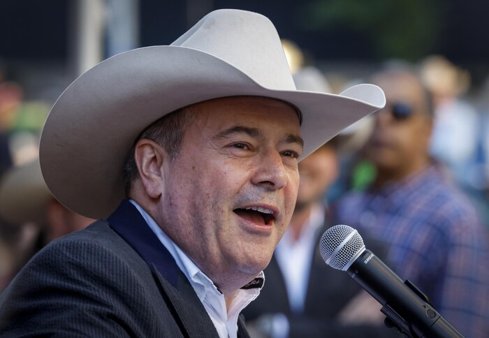Une personne avec un chapeau de cowboy parle dans un micro.