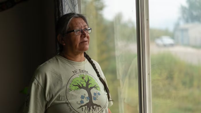 Sur cette photo de 2023, Jean L'Hommecourt, militante écologiste, regarde par la fenêtre des nuages de poussière s'abattant sur Fort McKay, dans le nord de l'Alberta.