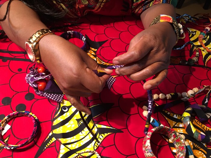Jeanne Zita tresse des bracelets aux couleurs vibrantes. 