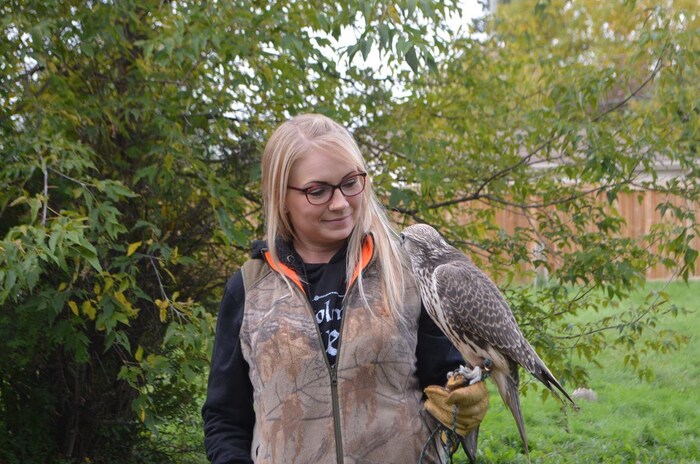 Une femme avec un oiseau posé sur sa main.