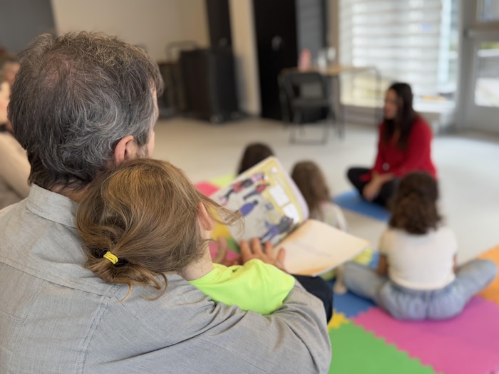 Une enfant et son papa &eacute;coutent un groupe de personnes.