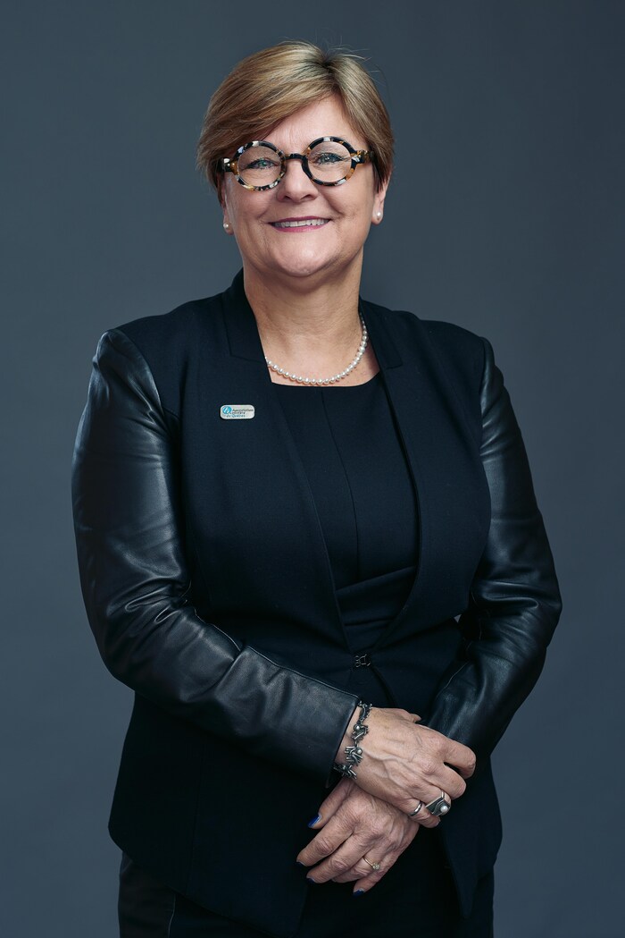 Une femme pose pour la caméra, souriante.