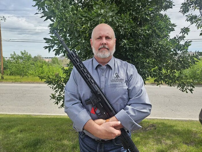 Un homme tient une arme d'assaut.