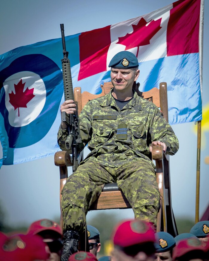 Le major Barling est en uniforme assis sur une chaise et tient une arme à feu.