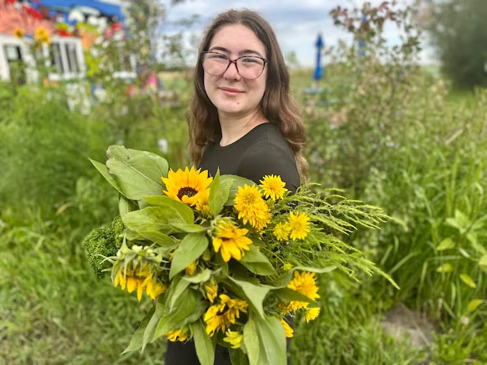 Une jeune femme cueillant des des fleurs pour composer un bouquet d'automne à Beaumont, en Alberta.