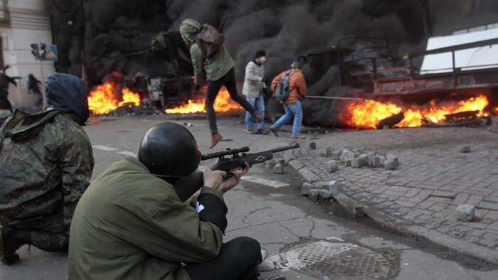 Un protestataire antigouvernemental tire durant des affrontements avec la police, près du parlement ukrainien.