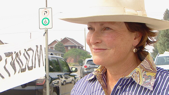 Une femme portant un large chapeau fixe le regard sur l'objectif d'une caméra, en Alberta, le 11 juin 2025.