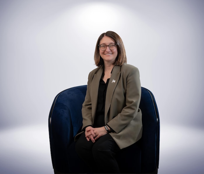 Une femme souriante est assise dans un fauteuil.