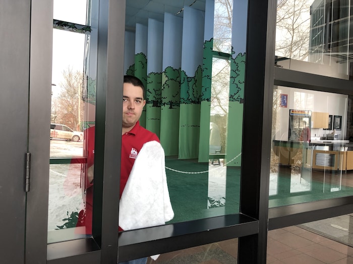 Un stagiaire nettoie les vitres du Musée.