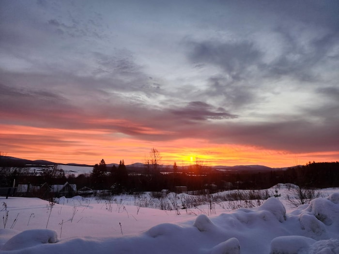 Un paysage hivernal avec le soleil qui se lève dans les montagnes.