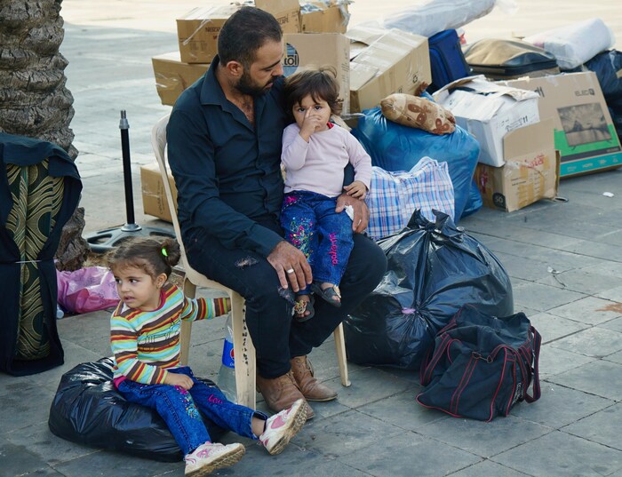 Un réfugiés syriens attend avec ses deux fillettes.