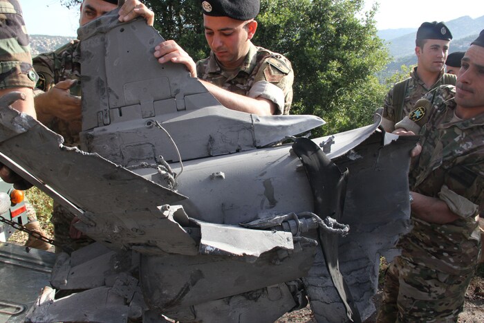 Plusieurs soldats tiennent et observent la carcasse d'un missile.