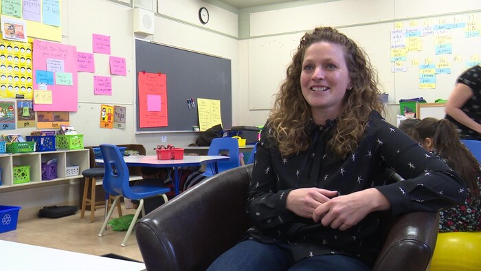 Une enseignante accorde une entrevue à la caméra dans une salle de classe.