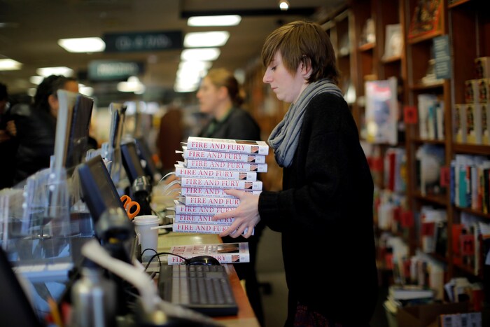 Une employée tient une dizaine d'exemplaires du livre dans ses mains. 