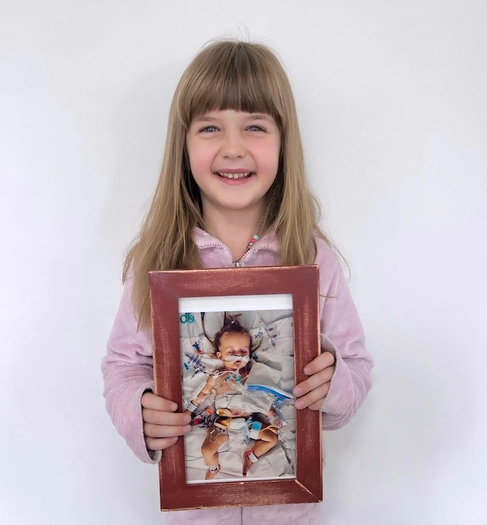 Une fillette, Lukah, tient une photo d'un bébé sur un lit d'hôpital.