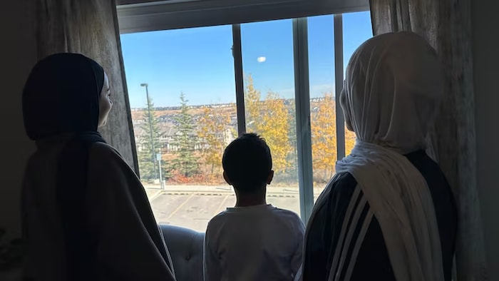 Trois personnes regardent à travers une fenêtre.